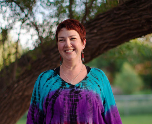 Photo of Karla Helbert standing in front of a tree. Karla offers yoga for those facing grief in the online course Bearing the Unbearable.