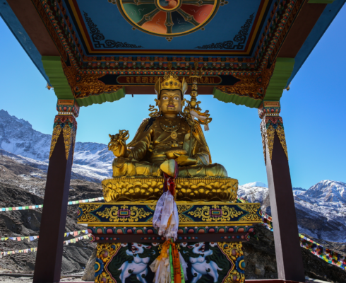 Gold statue of Padmasambhava with mountains in background